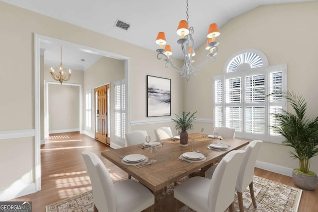 dining area featuring vaulted ceiling, a notable chandelier, and light hardwood / wood-style flooring