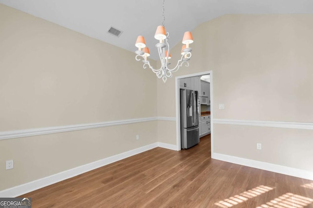 empty room featuring a notable chandelier and hardwood / wood-style floors