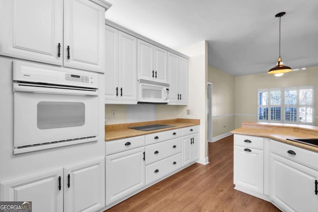 kitchen featuring white appliances, pendant lighting, white cabinets, and light hardwood / wood-style flooring