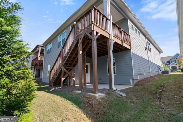 rear view of house with a deck, a yard, cooling unit, and a patio