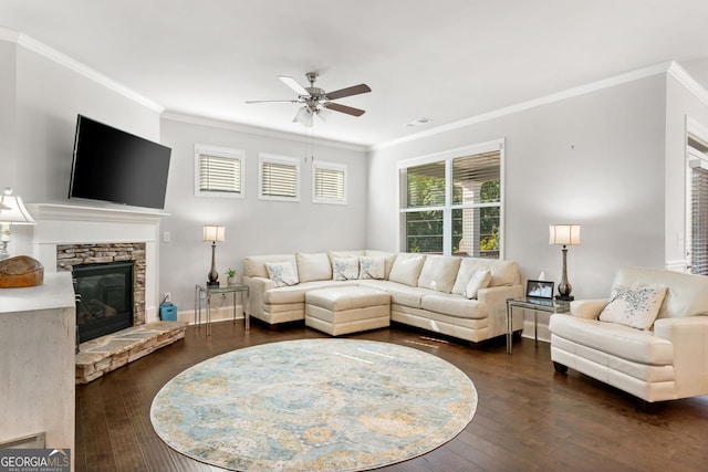 living room with ornamental molding, ceiling fan, dark hardwood / wood-style flooring, and a stone fireplace