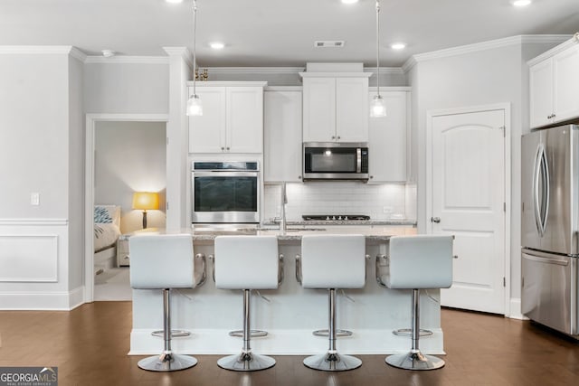 kitchen featuring stainless steel appliances, a kitchen island with sink, a breakfast bar area, and pendant lighting