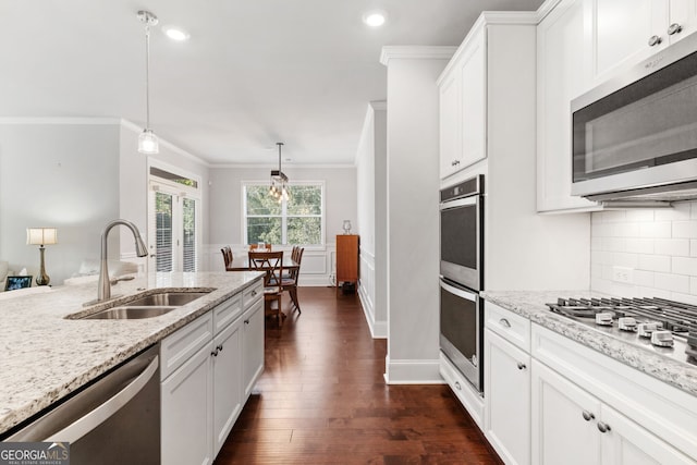 kitchen featuring white cabinets, appliances with stainless steel finishes, pendant lighting, and sink