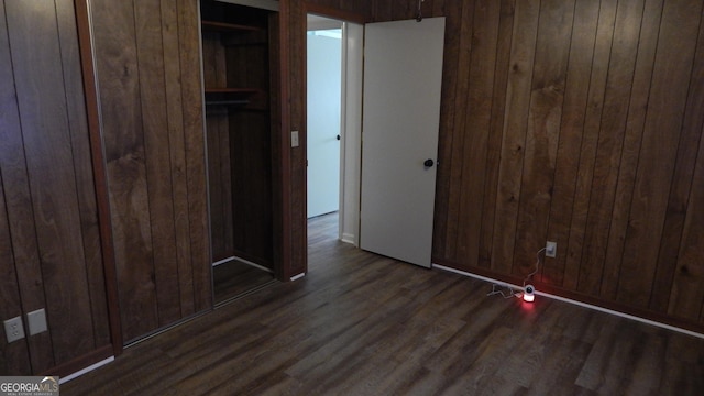 unfurnished bedroom with wood walls, a closet, and dark hardwood / wood-style flooring