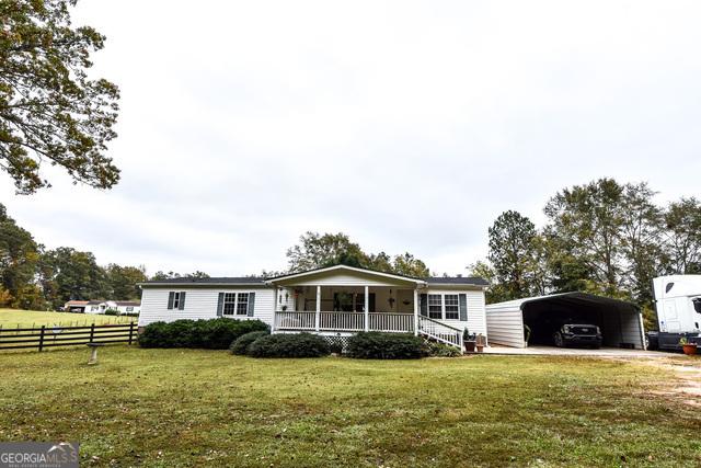 view of front of home with a front yard, covered porch, and a carport