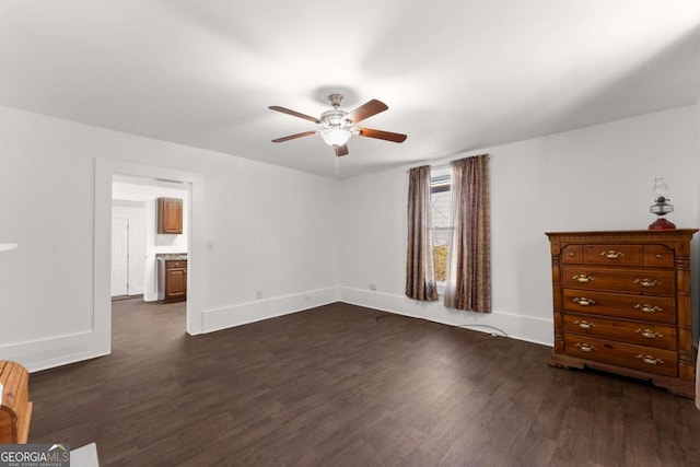 unfurnished bedroom featuring ensuite bath, ceiling fan, and dark wood-type flooring