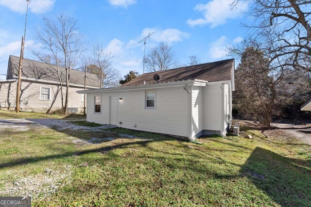 back of property featuring cooling unit and a lawn