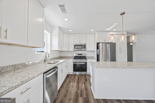 kitchen with light stone countertops, hanging light fixtures, white cabinetry, appliances with stainless steel finishes, and sink