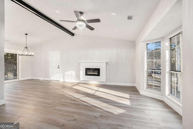 unfurnished living room with ceiling fan with notable chandelier, light hardwood / wood-style floors, a textured ceiling, and vaulted ceiling with beams