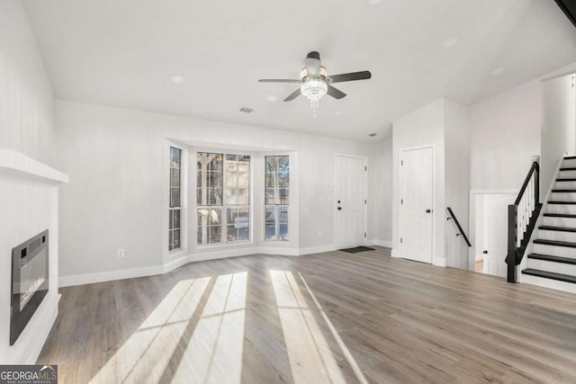 unfurnished living room with light hardwood / wood-style floors, ceiling fan, and heating unit