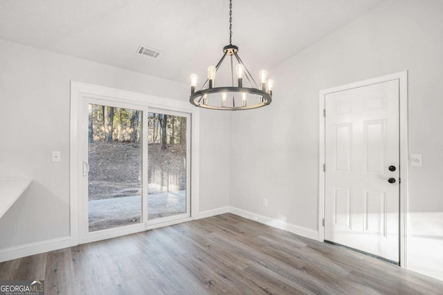 unfurnished dining area featuring wood-type flooring and a chandelier