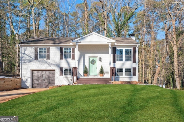 split foyer home featuring brick siding, concrete driveway, a chimney, an attached garage, and a front yard