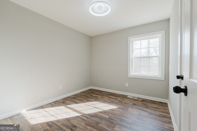 unfurnished room with visible vents, baseboards, and wood finished floors