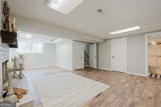 basement featuring light wood-type flooring, visible vents, and baseboards