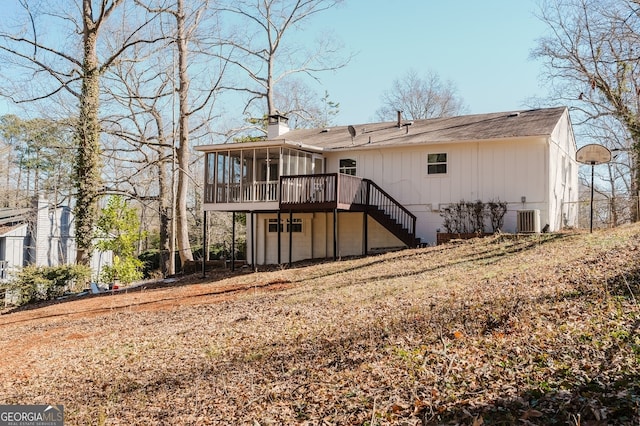 back of house featuring central air condition unit, a sunroom, a chimney, and stairway