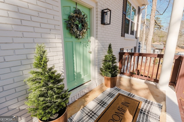 doorway to property with covered porch and brick siding