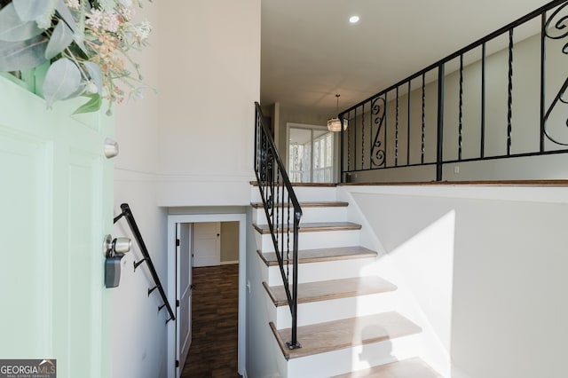 stairs featuring wood finished floors and recessed lighting