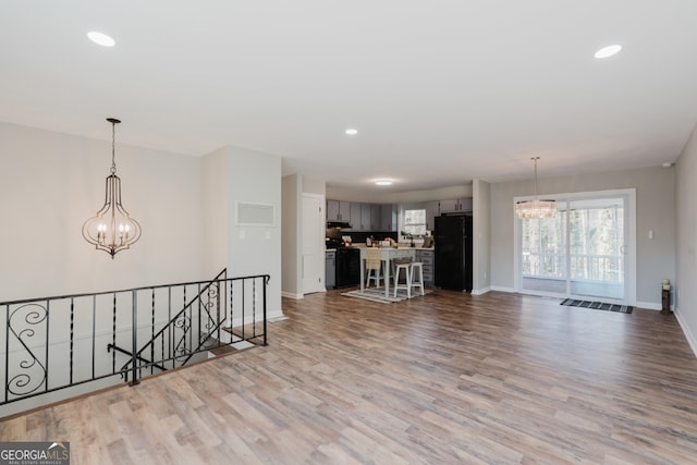 interior space featuring baseboards, light wood-style floors, an upstairs landing, and a notable chandelier