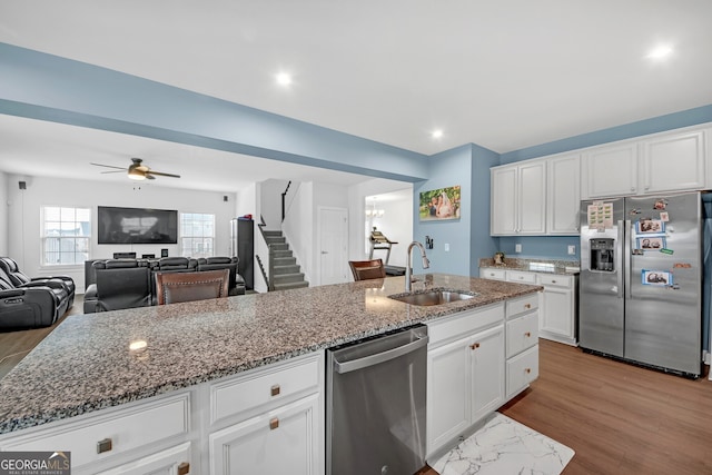 kitchen featuring appliances with stainless steel finishes, white cabinetry, a kitchen island with sink, and sink