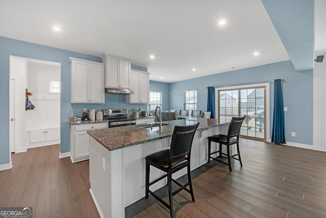 kitchen featuring an island with sink, stainless steel electric range, a breakfast bar area, white cabinets, and sink