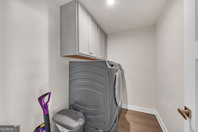 laundry room featuring dark wood-type flooring, washer and dryer, and cabinets