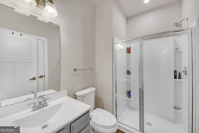 bathroom featuring toilet, a shower with door, and vanity