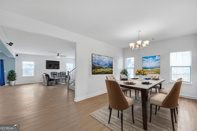 dining space featuring ceiling fan with notable chandelier, a wealth of natural light, and wood-type flooring