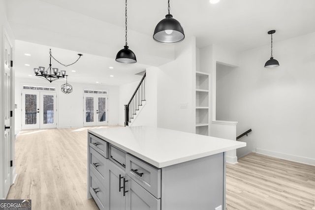 kitchen with gray cabinetry, light wood-type flooring, french doors, and pendant lighting