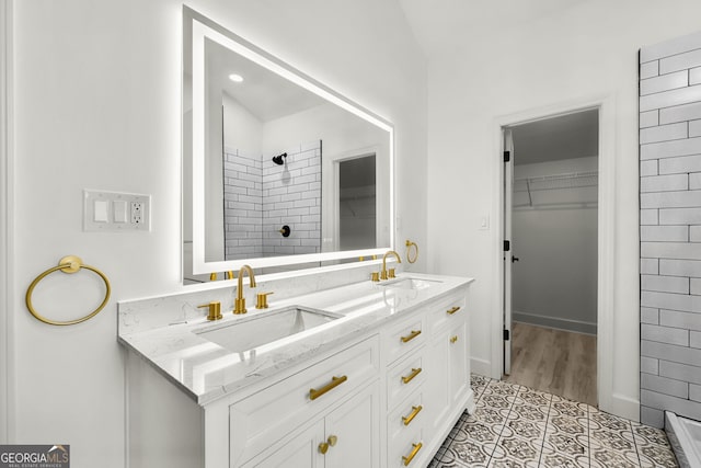 bathroom with tile patterned flooring, a tile shower, and vanity