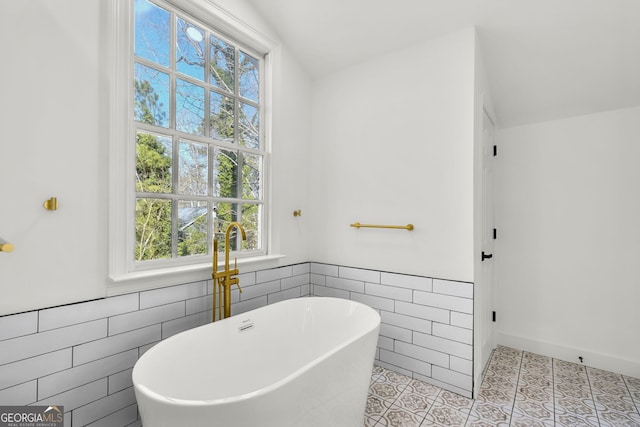 bathroom with lofted ceiling, tile walls, tile patterned floors, and a tub to relax in