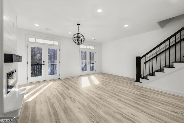 unfurnished living room featuring a notable chandelier, light hardwood / wood-style flooring, french doors, and heating unit