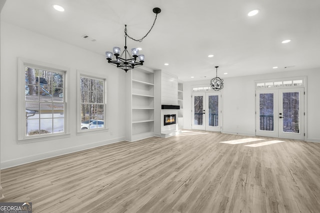 unfurnished living room with a healthy amount of sunlight, light hardwood / wood-style flooring, french doors, and built in shelves