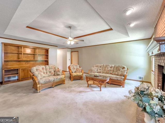 sitting room with a textured ceiling, a raised ceiling, crown molding, a fireplace, and light carpet