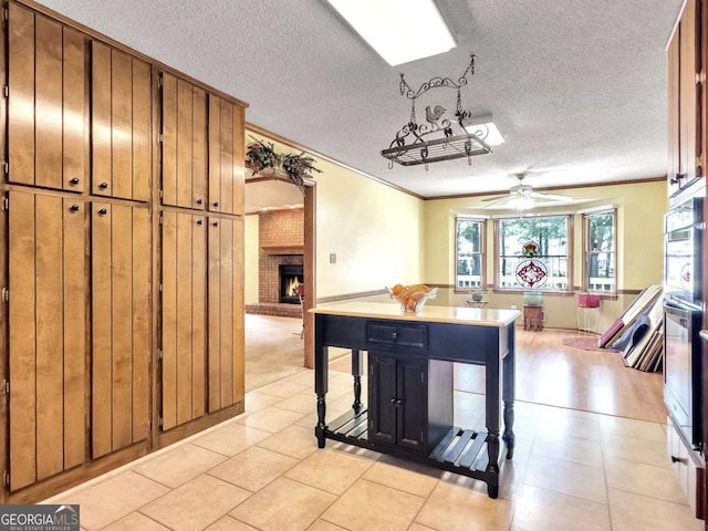 kitchen with a fireplace, ceiling fan, crown molding, and a breakfast bar area