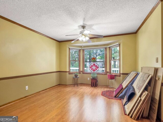 interior space with a textured ceiling, ornamental molding, and light hardwood / wood-style flooring