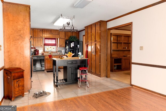 114 Tracy Ln, Mcdonough, GA 30253 - kitchen featuring crown molding, baseboards, light wood-style floors, black appliances, and brown cabinets
