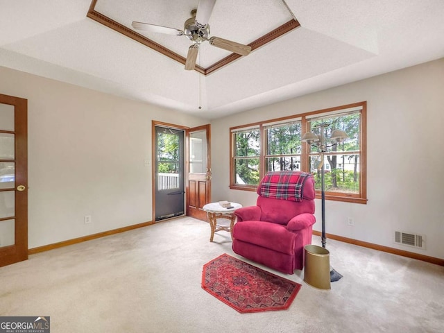 sitting room with a raised ceiling, ceiling fan, and carpet