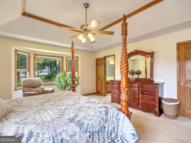 bedroom featuring a textured ceiling, ceiling fan, a tray ceiling, and light colored carpet