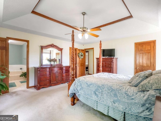 bedroom with ensuite bathroom, carpet flooring, ceiling fan, and a tray ceiling