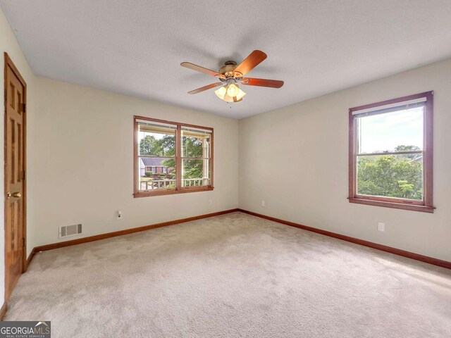 carpeted spare room featuring ceiling fan and a healthy amount of sunlight