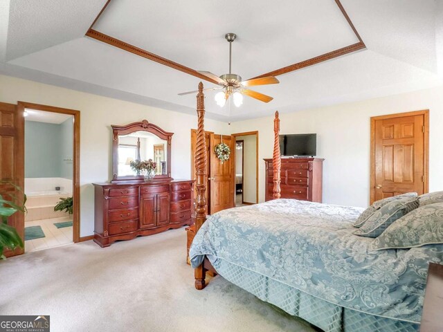 bedroom featuring connected bathroom, carpet flooring, ceiling fan, and a tray ceiling