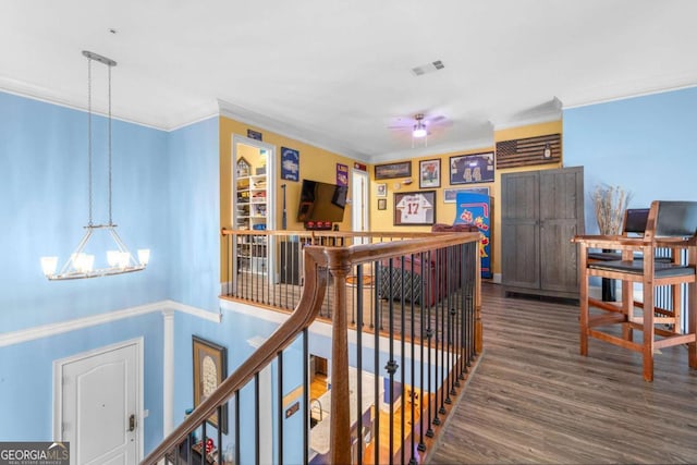 hallway with a notable chandelier, hardwood / wood-style flooring, and crown molding