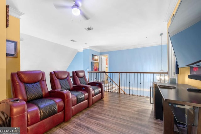 cinema with wood-type flooring, ceiling fan, and crown molding