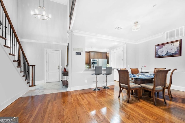 dining space featuring ornamental molding, light hardwood / wood-style flooring, and an inviting chandelier