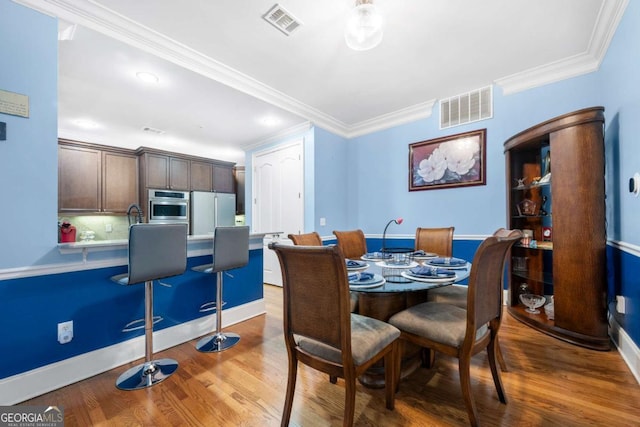 dining space featuring hardwood / wood-style floors and ornamental molding