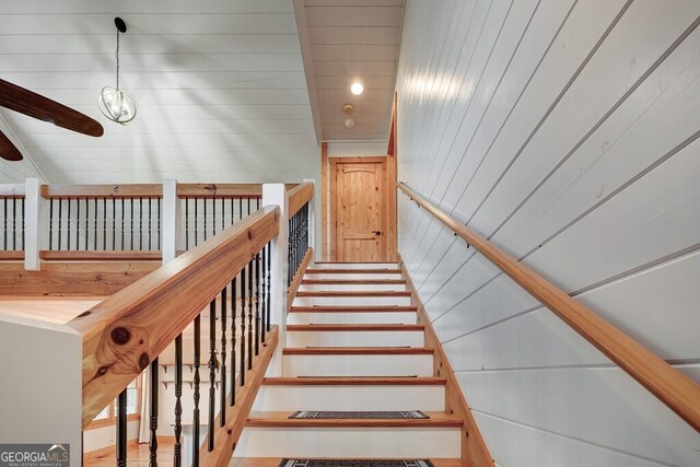 stairway featuring wood walls and an inviting chandelier