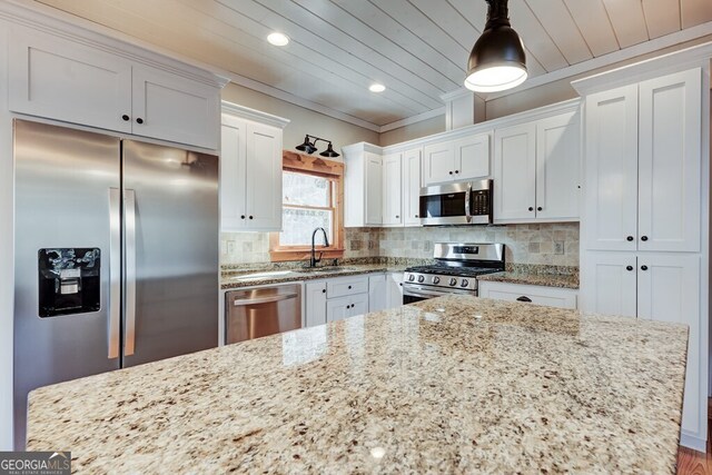 kitchen with decorative backsplash, appliances with stainless steel finishes, pendant lighting, and white cabinetry