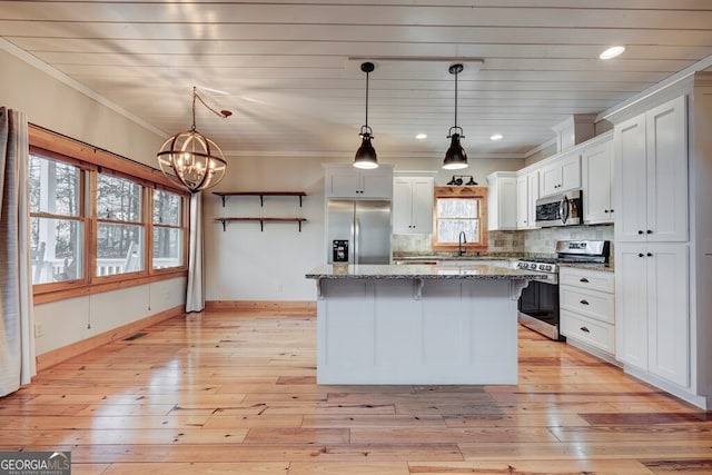 kitchen with a kitchen island, white cabinetry, hanging light fixtures, and appliances with stainless steel finishes