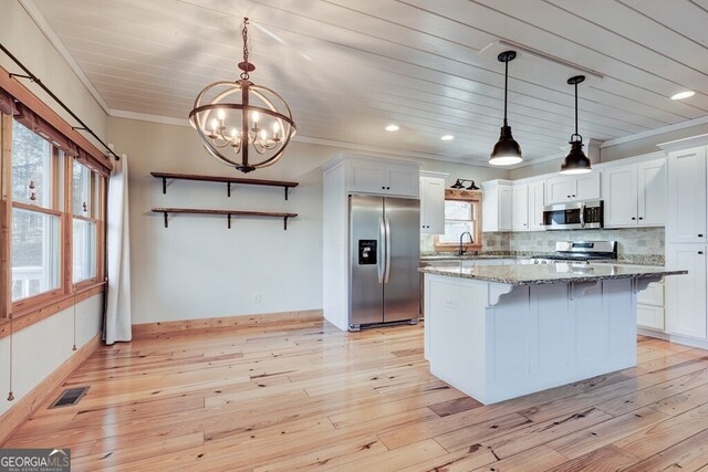 kitchen with appliances with stainless steel finishes, white cabinets, dark stone countertops, and pendant lighting