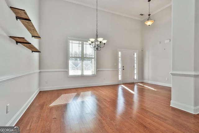 foyer featuring ornamental molding, a towering ceiling, a chandelier, and wood-type flooring